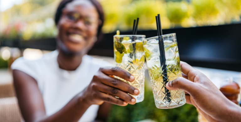 Beautiful young black couple drinking hydrating mocktails in a bar outdoors. Having a celebratory toast.